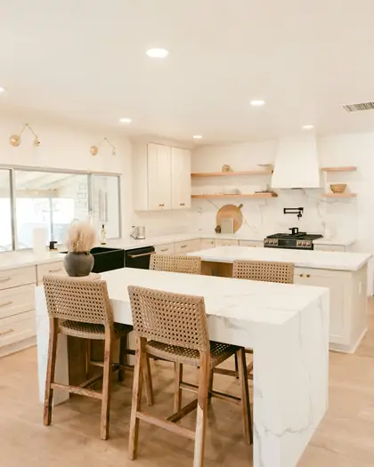 Bright kitchen with a marble island and woven stools